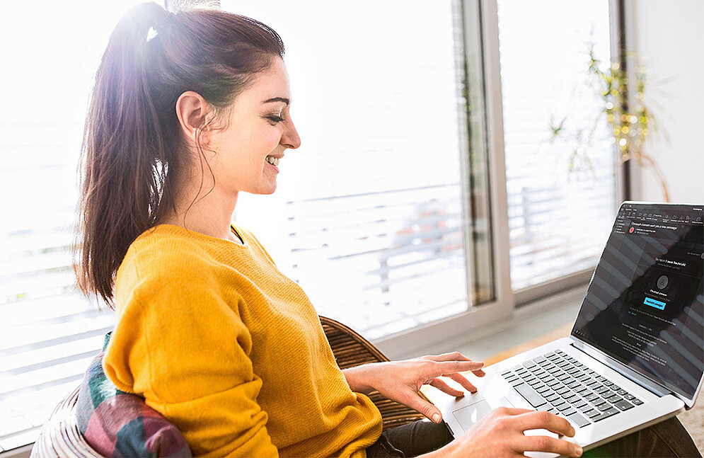 Phishing simulation strengthens security awareness Happy woman with laptop on lap